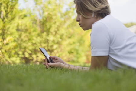 Young woman with headphones using smart phone in grass