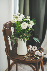 Spring white buttercup flowers in white enamel jug at home