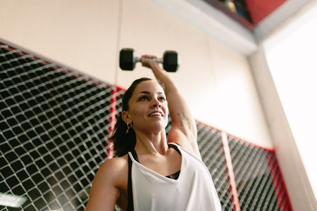 Fitness smiling woman lifting a dumbbell in the gym