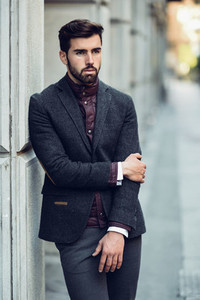 Young bearded man in urban background wearing british elegant suit in the street