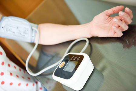 Woman measuring her own blood pressure at home