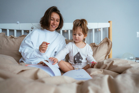 Mom and daughter draw in bed