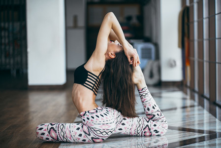 Young attractive woman practicing yoga near window
