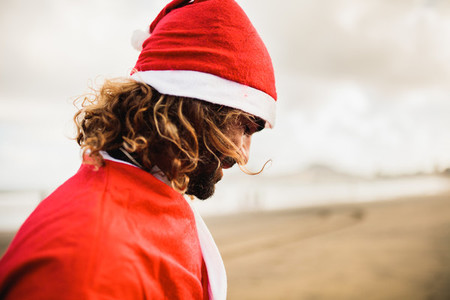 Young blonde man dresses up Santa Claus on the beach