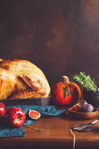 Festive table for Thanksgiving Holiday with whole roasted turkey with apple pumpkin figs and herbs in a mortar