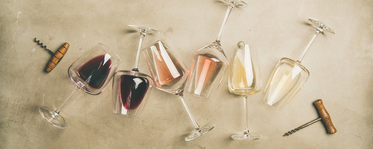 Different wines in glasses and corkscrews over grey background