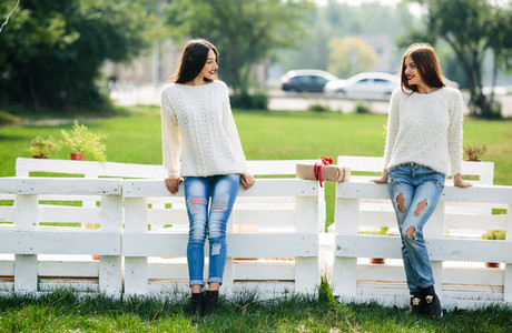 Two girls lean bench