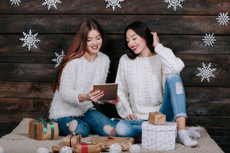 Two beautiful girls with a tablet between gifts