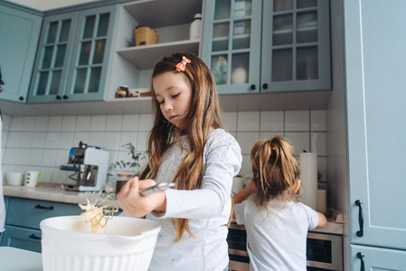 two little girls cook in the kitchen