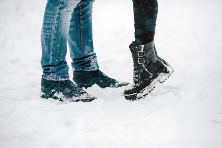 legs embracing couples standing on the snow