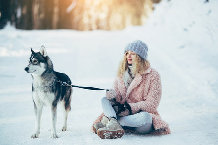 Beautiful girl with dog Husky in snowy woods