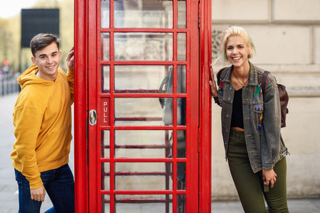 Young couple of friends near a classic British red phone booth