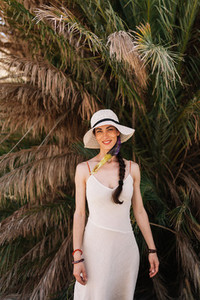 Smiling woman wearing dress standing close to palm tree