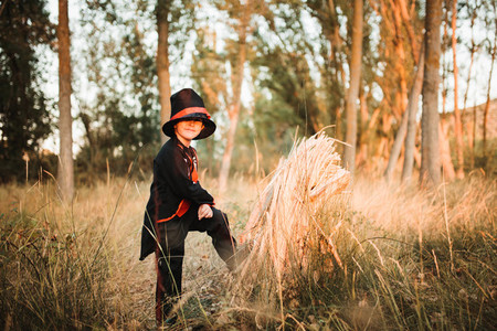 Boy disguised to halloween in the forest supported on a log