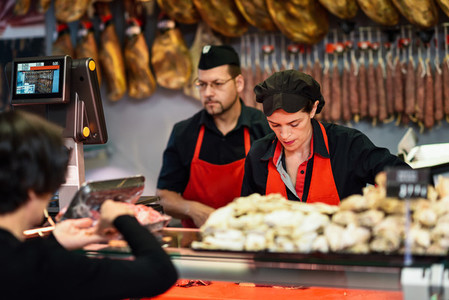 Butchers attending a customer in a butchers shop