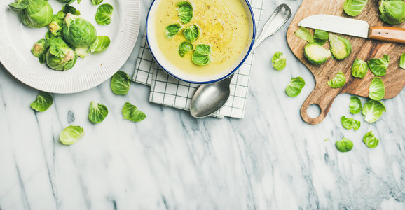 Brussels sprouts vegetable cream soup in bowl over marble background