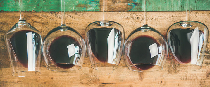 Red wine in glasses over rustic wooden background