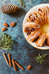 Creative flat lay top view of Swedish tea ring Christmas cake with cinnamon pecans and raisins on a blue background The concept of cozy winter Holidays and homemade bakery