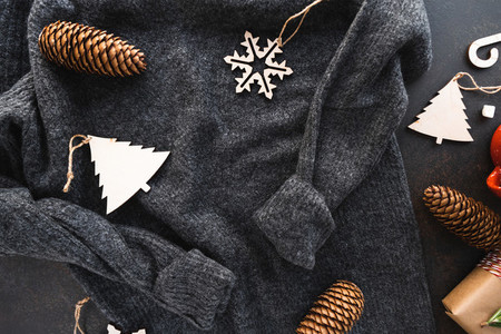 Top view of Christmas or winter time flat lay with grey warm woolen sweater  fir cones and wooden toys