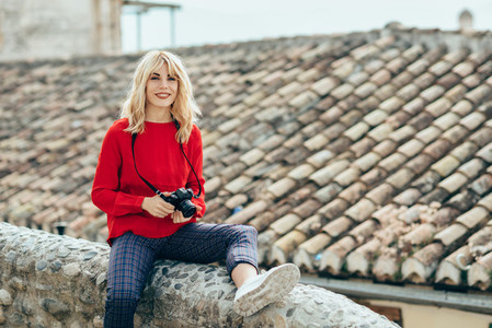 Young woman taking photographs with an old camera in a beautiful city