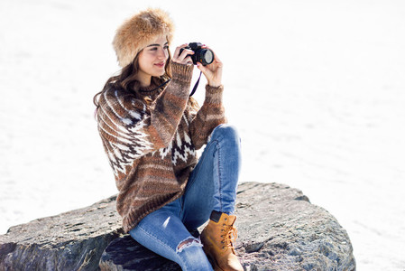 Young woman taking photographs in the snowy mountains