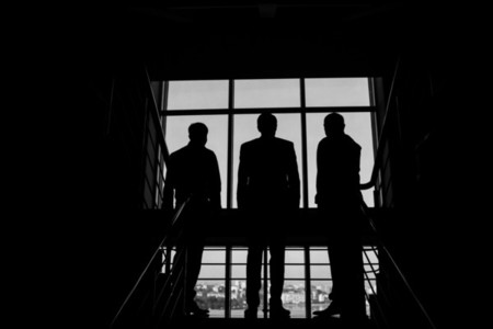 Three businessmen standing at the window with a city view