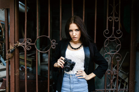 Beautiful girl standing against a wall with a camera