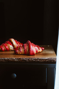 Two cherry croissants are served on a rustic wooden board  Moody food photography