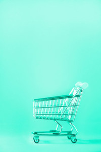 Shopping cart on mint color background  Minimalism style  Creative design  Copy space  Shop trolley at supermarket  Sale  discount  shopaholism concept  Trendy green and turquoise color