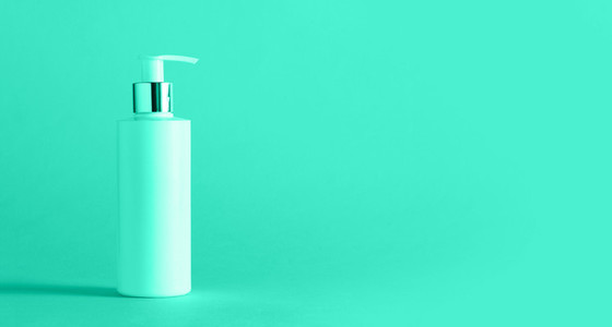 White bottle of moisturizing lotion on mint color background with copy space  Minimalism style  Trendy green and turquoise color  Skin care  body treatment  beauty concept