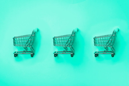 Shopping cart on mint color background  Minimalism style  Creative design  Shop trolley at supermarket  Trendy green and turquoise color  Sale  discount  shopaholism concept