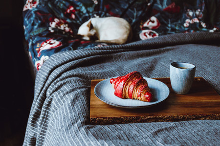 Cherry croissant with a cup of espresso on a wooden tray in a bed  The concept of cozy morning at home
