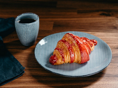Cherry croissant with a cup of espresso on a rustic wooden table