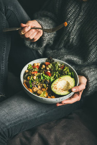 Woman holding bowl with salad avocado beans and vegetables