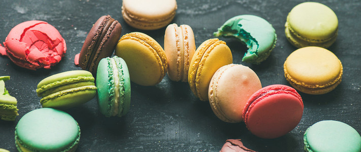 Colorful French macaroons over black background  wide composition
