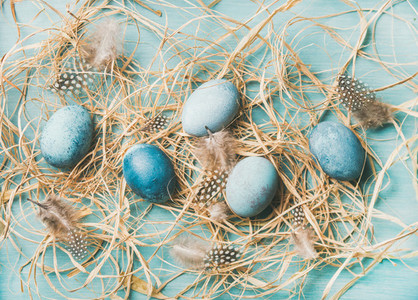 Blue painted traditional eggs for Easter holiday in hay