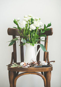 Spring white buttercup flowers in white enamel jug