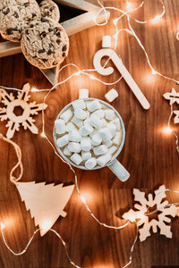 Cozy Christmas or New Year  flat lay Hot chocolate with marshmallow in a white ceramic mug among winter decor and lights