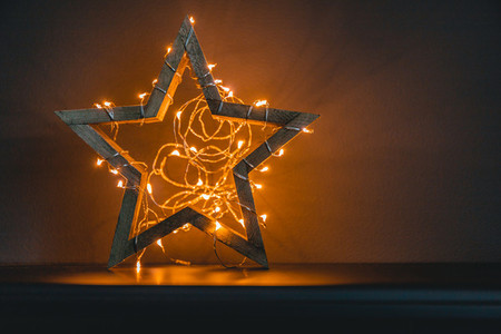 Wooden shiny star with a festoon as a symbol of New Year Holidays and Christmas  Copy space