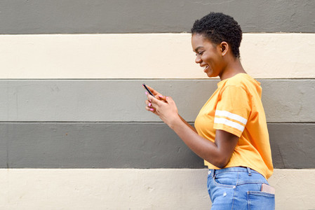 Young black woman laughing using her smart phone outdoors