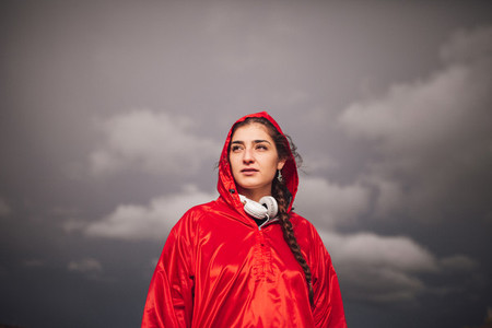Young woman standing with raincoat and headphones on the field