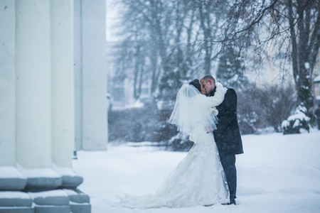 Bride and groom walking on the European city in the snow