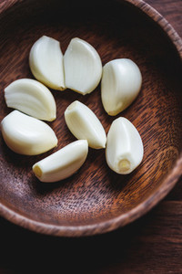 Macro food photography of peeled garlic cloves in a wooden bowl  Top view