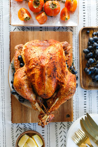 Roasted whole turkey on a table with persimmon  blue grape and lemon for family Thanksgiving Holiday  Top view  flat lay