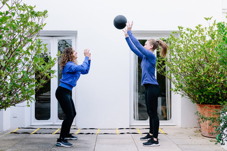 Two young women doing exercise together with medicine ball