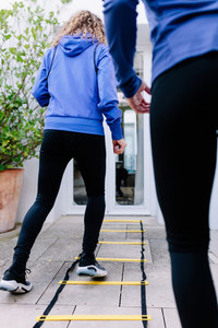 Two young women doing agility ladder exercise on a terrace