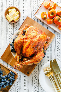 Roasted whole turkey on a festive table with persimmon blue grape and lemon for family Thanksgiving Holiday Top view flat lay