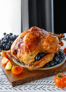Roasted whole turkey on a table with persimmon  blue grape and lemon for family Thanksgiving Holiday