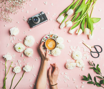 Female hands holding coffee  fresh flowers and film camera