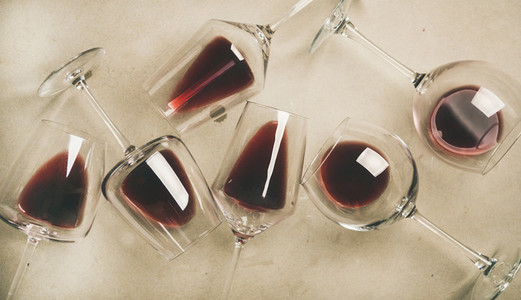 Flat lay of red wine in glasses over grey concrete background
